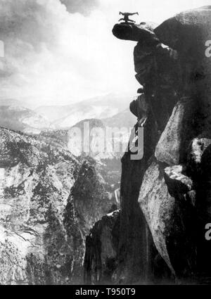 Jeune homme en équilibre sur la tête au sommet de Glacier Point. Glacier Point est un point au-dessus de la vallée Yosemite, en Californie, États-Unis. Il est situé sur le mur sud de la vallée Yosemite, à une altitude de 7 214 pieds. Le point offre une vue superbe sur plusieurs de Yosemite National Park est bien connue comme la vallée Yosemite, Yosemite Falls, demi-dôme, Automne, Nevada Vernal Fall, et les nuages se reposer. Années 1890 Banque D'Images