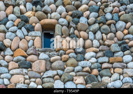 Différents types de pierres et de cailloux de taille similaire organisé autour de petite fenêtre dans le mur extérieur d'un bâtiment Banque D'Images