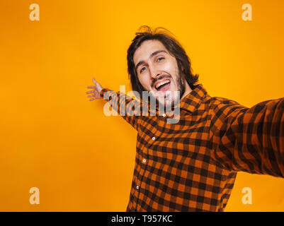 Portrait of smiling man wearing plaid shirt réjouissance et de prendre tout en photo selfies isolés sur fond jaune en studio Banque D'Images