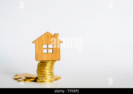 Symbole de la maison est faite de bambou sur une pile de pièces brillantes jaunes sur un fond clair. Concept de l'offre d'achat immobilier. Copier l'espace. Banque D'Images