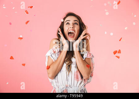 Image de cute woman wearing dress 20s kissing sous les confettis, isolé sur fond rose Banque D'Images