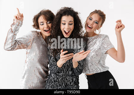 Image d'une belle jeune femme choqué excité happy friends posing isolated over white background mur à l'aide de téléphone mobile sur une partie. Banque D'Images