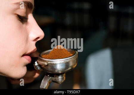 La meilleure odeur dans le monde entier. Femme portafilter barista tenir dans la main. Renifler l'odeur de la femme du café frais. Barista espresso brew Banque D'Images