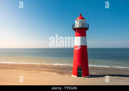 Un phare rouge et blanc en mer sous un ciel bleu clair près de Westkapelle en Zélande, aux Pays-Bas. Banque D'Images