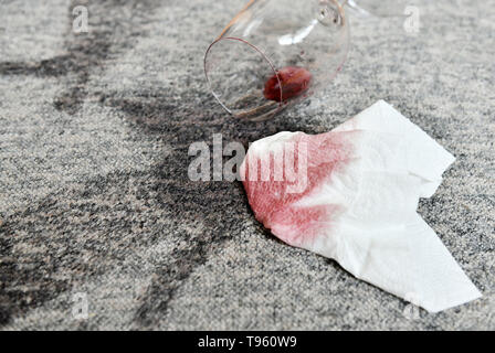 Osterode am Harz, Allemagne. 16 mai, 2019. ILLUSTRATION - un verre avec un peu de vin rouge se trouve sur un tapis à côté de taches fraîches et d'une serviette en papier. Frank May/alliance photo Credit : Frank May/photo de l'alliance/dpa/Alamy Live News Banque D'Images