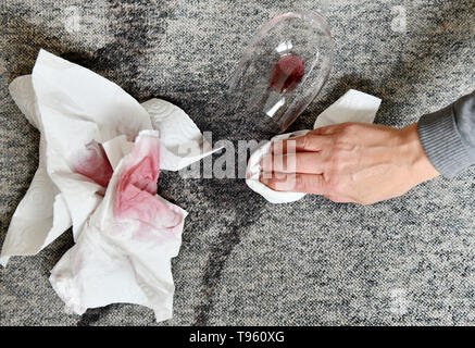 Osterode am Harz, Allemagne. 16 mai, 2019. ILLUSTRATION - un verre à vin rouge se trouve sur un tapis à côté de fresh les taches tout en essayant d'enlever les taches avec du papier absorbant. Frank May/alliance photo Credit : Frank May/photo de l'alliance/dpa/Alamy Live News Banque D'Images