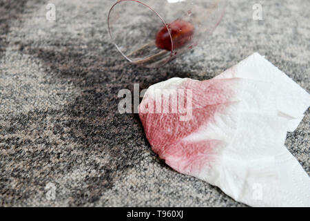 Osterode am Harz, Allemagne. 16 mai, 2019. ILLUSTRATION - un verre avec un peu de vin rouge se trouve sur un tapis à côté de taches fraîches et d'une serviette en papier. Frank May/alliance photo Credit : Frank May/photo de l'alliance/dpa/Alamy Live News Banque D'Images