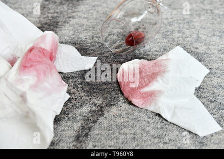 Osterode am Harz, Allemagne. 16 mai, 2019. ILLUSTRATION - un verre avec un peu de vin rouge se trouve sur un tapis à côté de taches fraîches et d'une serviette en papier. Frank May/alliance photo Credit : Frank May/photo de l'alliance/dpa/Alamy Live News Banque D'Images