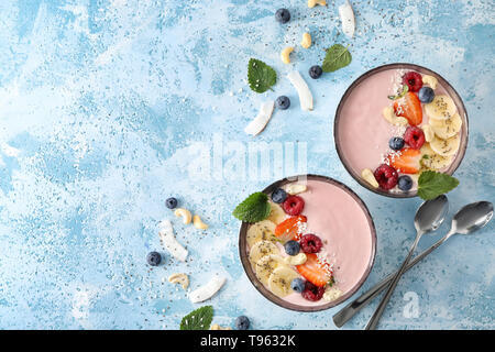 Bols avec du yaourt rose et fruits frais sur la table de couleurs Banque D'Images