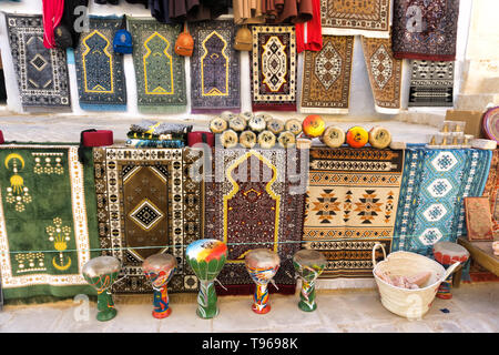 Des tapis colorés et d'autres souvenirs à vendre dans une rue de Kairouan, Tunisie. Banque D'Images