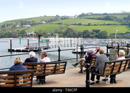 Des gens assis sur des bancs en profitant de la vue sur l'estuaire à Salcombe waterfront sur une journée d'été,Devon England UK Banque D'Images