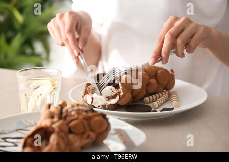 Woman eating sweet bubble waffle à table Banque D'Images