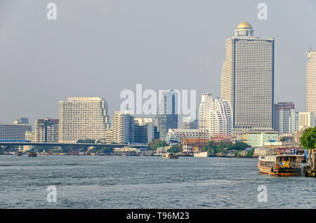 Bangkok, Thaïlande - 18 Avril 2018 : Chao Phraya, avec des bateaux, pont Taksin avec le Skytrain et célèbres bâtiments gratte-ciel à usage mixte - Remorquage Gems Banque D'Images