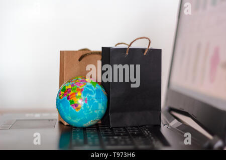 Sacs shopping et world globe sur clavier d'ordinateur portable. Dans le monde des achats en ligne, e-commerce concept Banque D'Images