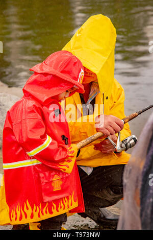 Un père Américain asiatique tente d'expliquer la technique de l'utilisation d'une canne à pêche pour son petit garçon sur un jour de pluie dans la région de Fountain Valley, CA. Banque D'Images