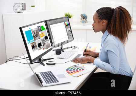 Jeune femme Designer Édition de photos sur Computer in Office Banque D'Images