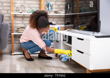 Smiling Young Woman Cleaning Meubles avec serviette Banque D'Images