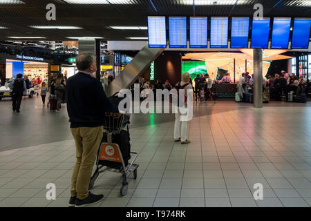 Les passagers qui s'enregistrent les tableaux des départs à l'aéroport de Schiphol, Amsterdam, Pays-Bas Banque D'Images