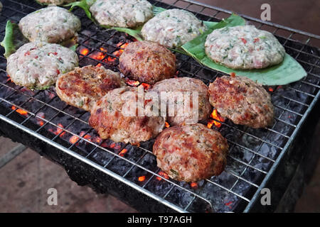 L'ouette escalopes poêlées sur une feuille verte sont frites dans la rue sur un grill. L'alimentation de rue en Asie. La préparation aux épices escalope de boeuf sur le grill pour ha Banque D'Images