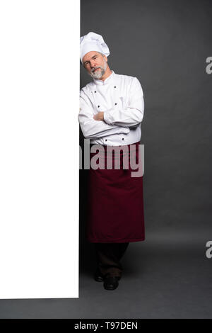 Full Length portrait of a happy chef cuisinier montrant copyspace sur les paumes isolé sur fond noir. Banque D'Images