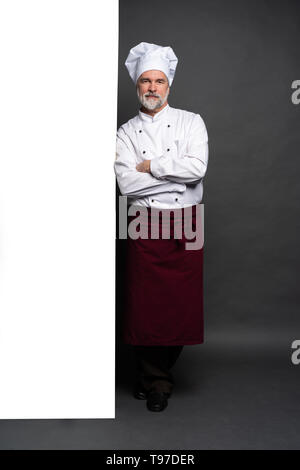 Full Length portrait of a happy chef cuisinier montrant copyspace sur les paumes isolé sur fond noir. Banque D'Images