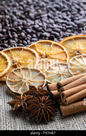 Avec les grains de café et lime orange séchée des bâtons de cannelle et d'anis étoilé sur l'arrière-plan de la lumière de la toile de jute Banque D'Images