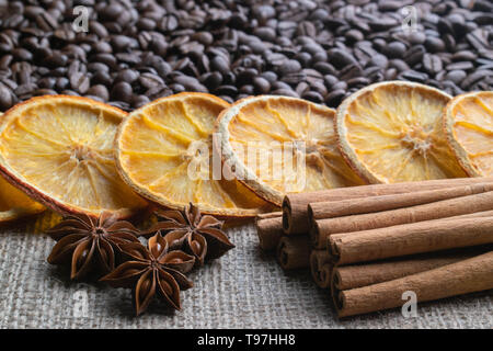 Avec les grains de café d'agrumes d'orange séchée des bâtons de cannelle et d'anis étoilé sur l'arrière-plan de la lumière de la toile de jute Banque D'Images