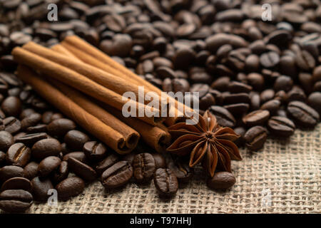 Café en grains avec star aniseas et des bâtons de cannelle sur la lumière de la toile de jute Banque D'Images