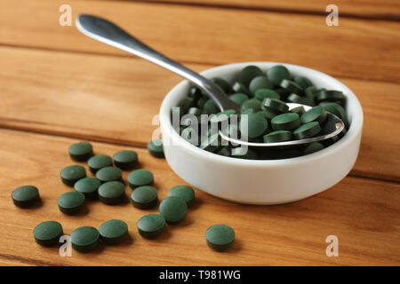 Bol et cuillère avec spirulina tablets on wooden table Banque D'Images