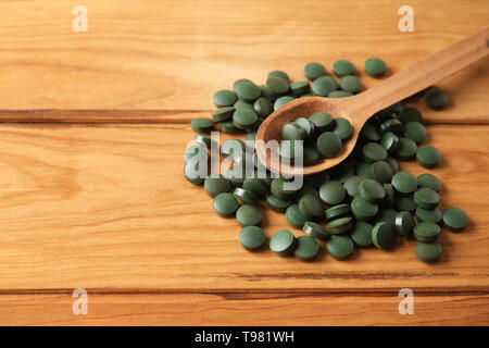 Les comprimés de spiruline avec cuillère sur table en bois Banque D'Images