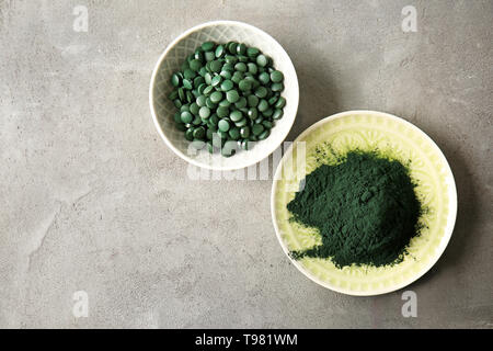 Les plaques avec la spiruline en comprimés et poudre sur table gris Banque D'Images
