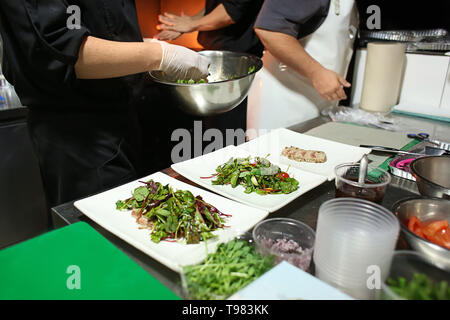 Le chef préparer une salade fraîche avec du poisson grillé pour servir dans la cuisine Banque D'Images