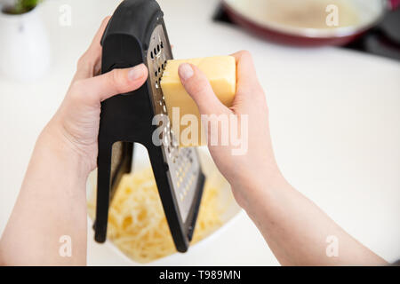 Femme sur une râpe à fromage grilles dans la cuisine. Banque D'Images