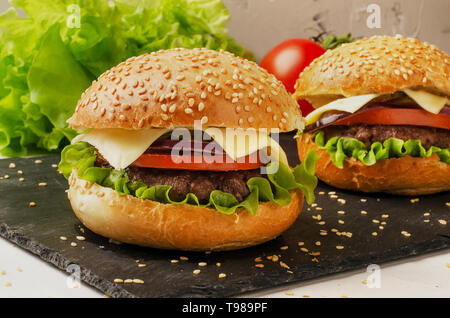 Close-up de burgers faits maison avec de la salade et les tomates sur une planche à découper Banque D'Images