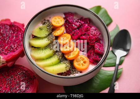 Yaourt avec différents fruits dans un bol sur un fond de couleur Banque D'Images