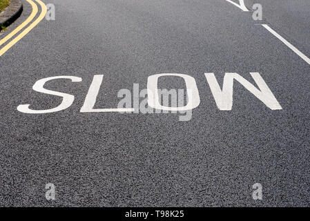 Faible signalisation panneau d'avertissement, fraîchement peint récemment mis sur le tarmac noir. Panneau d'avertissement lent le marquage routier peint sur la surface de la route. De nouveau. Fresh Banque D'Images