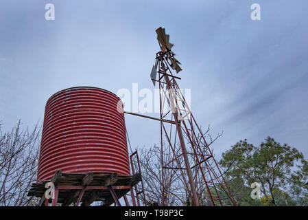 Un vieux moulin en fer sur une ferme dans l'ouest de la Nouvelle-Galles du Sud, tourne dans le vent sur une journée avec un ciel couvert de nuages gris strié, au-dessus Banque D'Images