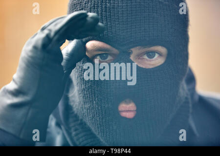 Einsatzkraft avec SEK Police masque tempête regarde à travers une fenêtre dans une maison Banque D'Images