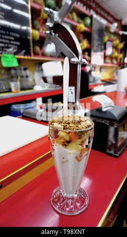 Jugos Canadå, Mexico. Bar à jus. Coupe de fruits tropicaux du yaourt avec du miel, granola, ananas, papayes et autres fruits rouge brillant sur le comptoir. Banque D'Images