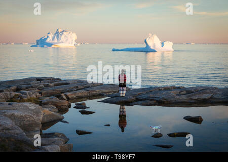 Femme Inuit en vêtements traditionnels se dresse sur la rive de la baie de Disko au Groenland, au milieu de l'été Banque D'Images