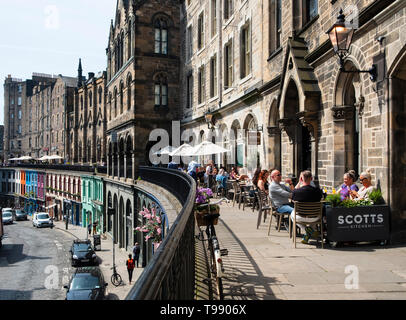 Les gens de boire et manger dans les restaurants de beau temps sur la terrasse au-dessus de Victoria Victoria Street dans la vieille ville d'Édimbourg, Écosse, Royaume-Uni Banque D'Images