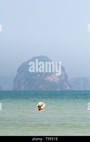 Femme au chapeau de paille dans la mer dans swiming Krabi Railey Beach donnant sur le port et les montagnes, la Thaïlande. Orientation verticale Banque D'Images