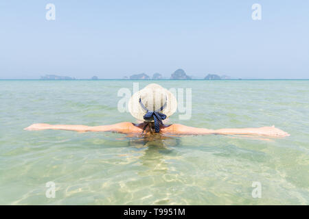 Femme au chapeau de paille dans la mer dans swiming Krabi Railey Beach donnant sur le port et les montagnes, la Thaïlande. Banque D'Images