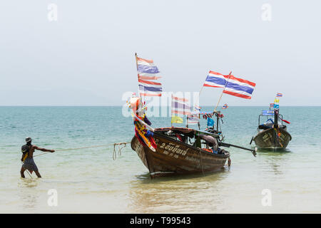 Krabi, Thaïlande - Mars 2019 : longue queue des bateaux en bois avec des drapeaux thaïlandais amarré à Railay beach. Banque D'Images