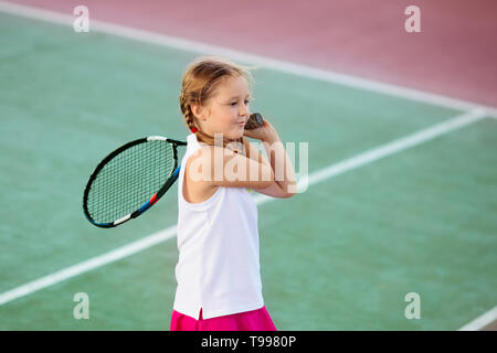 Enfant jouant au tennis sur un court intérieur. Petite fille avec raquette de tennis et la balle dans le sport club. Exercice actif pour les enfants. Activités d'été pour les enfants. Banque D'Images