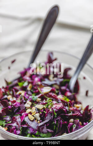 Salade de chou bleu frais avec les herbes et les noix dans un bol en verre sur une nappe rustique. Verser sur la sauce. Concept d'aliments sains et nutritifs Banque D'Images