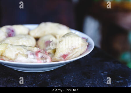 Quenelles avec les cerises dans un plat sur une sombre rétro arrière Banque D'Images