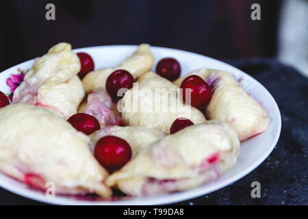 Quenelles avec les cerises dans un plat sur une sombre rétro arrière Banque D'Images