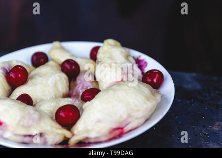 Quenelles avec les cerises dans un plat sur une sombre rétro arrière Banque D'Images