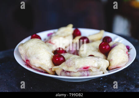 Quenelles avec les cerises dans un plat sur une sombre rétro arrière Banque D'Images